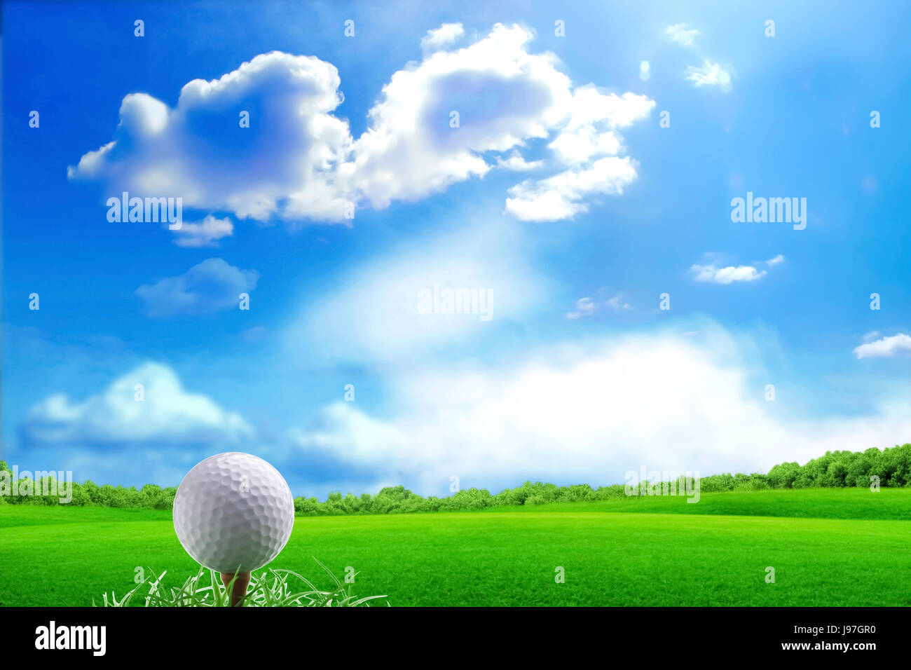 Golf ball and tee on green grass, beautiful bright blue sky Stock Photo