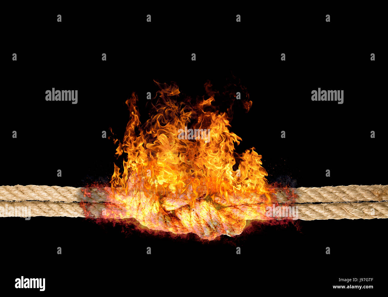 Strong rope with a knot, bursted into flames, isolated against the black colored background Stock Photo