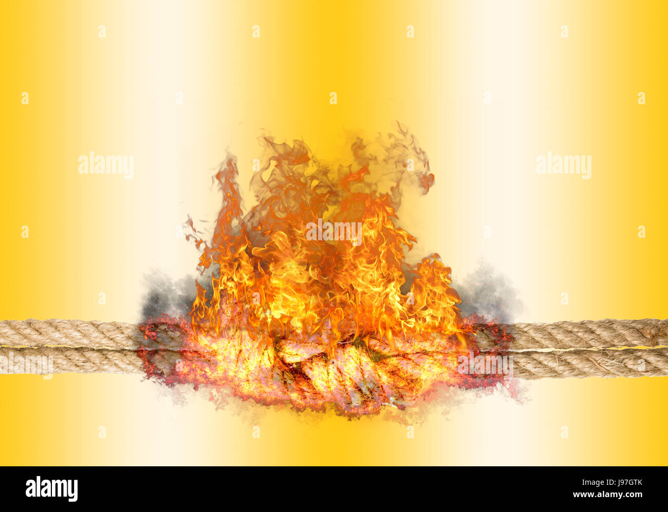 Strong rope with a knot, bursted into flames, isolated against the golden colored background Stock Photo