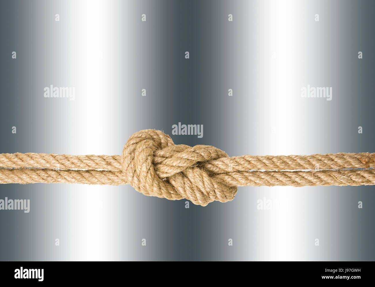 Strong rope with a knot, isolated against the silver colored background Stock Photo