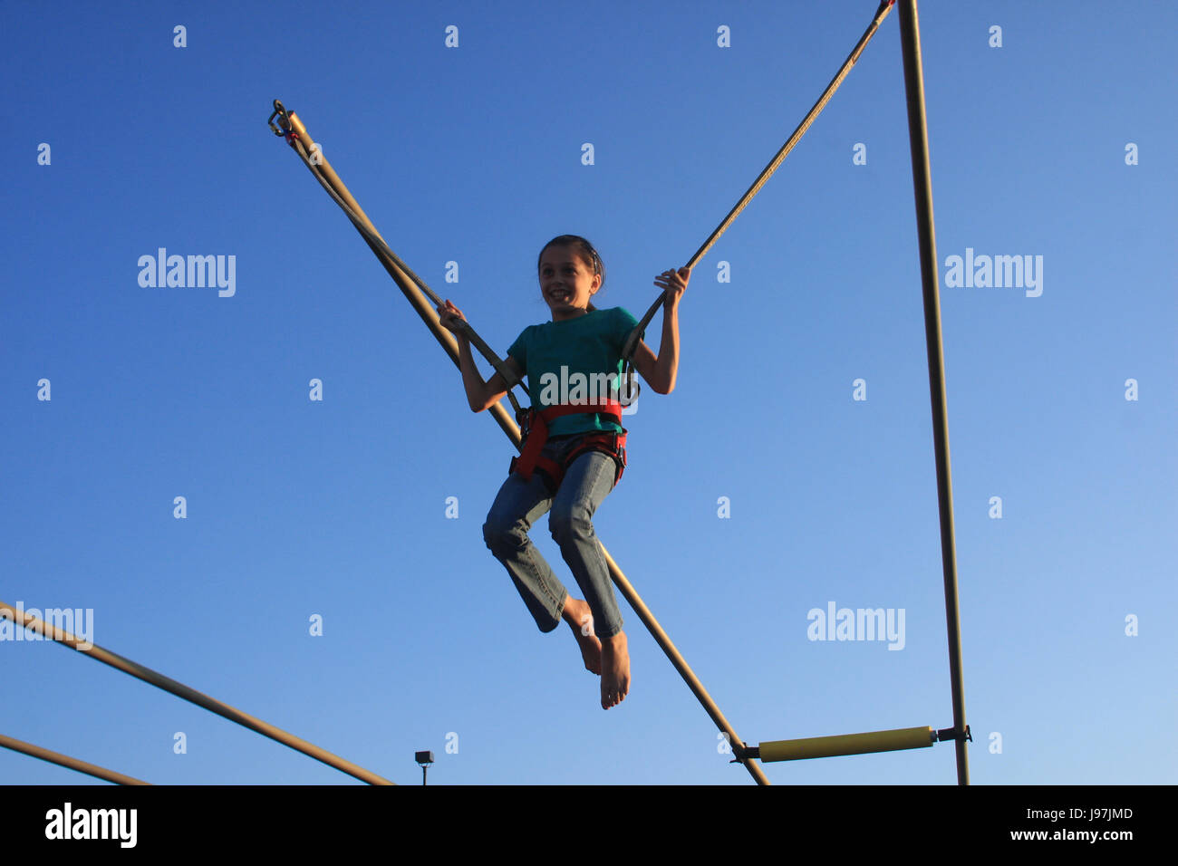 Happy girl jumping on trampoline; bungee jumping Stock Photo Alamy