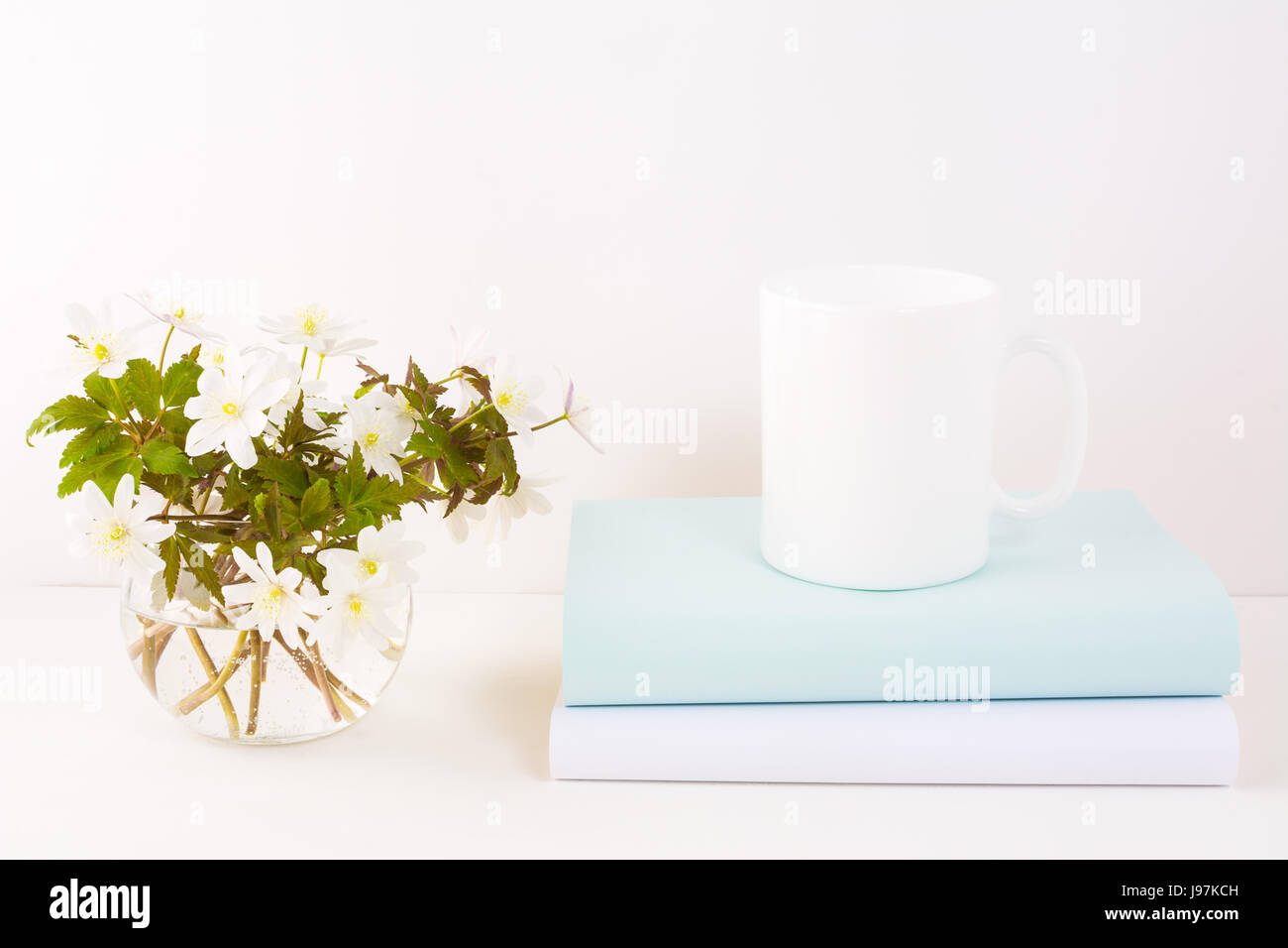 White coffee mug mockup with blooming Rue Anemone.  Empty mug mock up for design promotion. Stock Photo