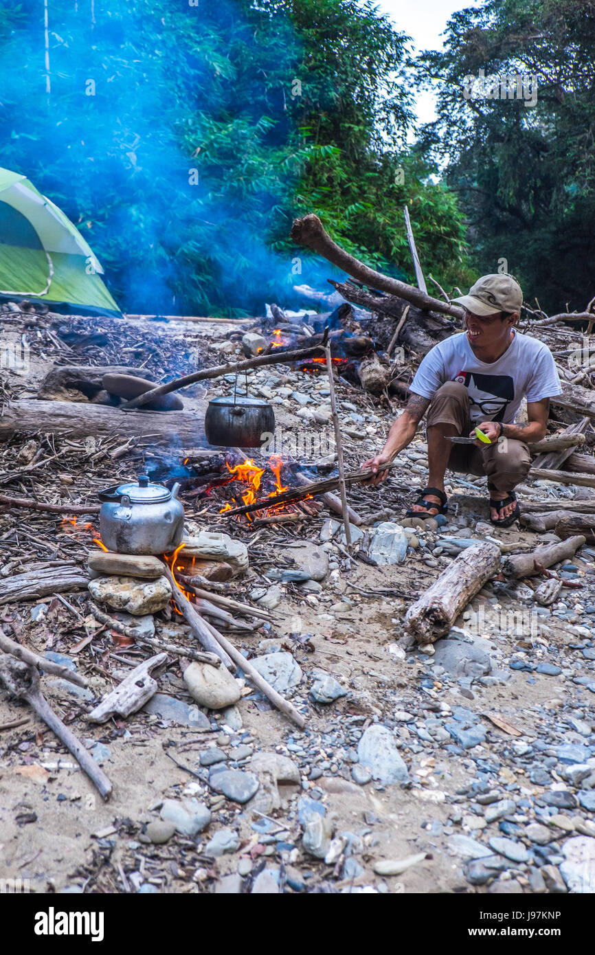 Camper setting up campfire to cook meal at camp site in the remote