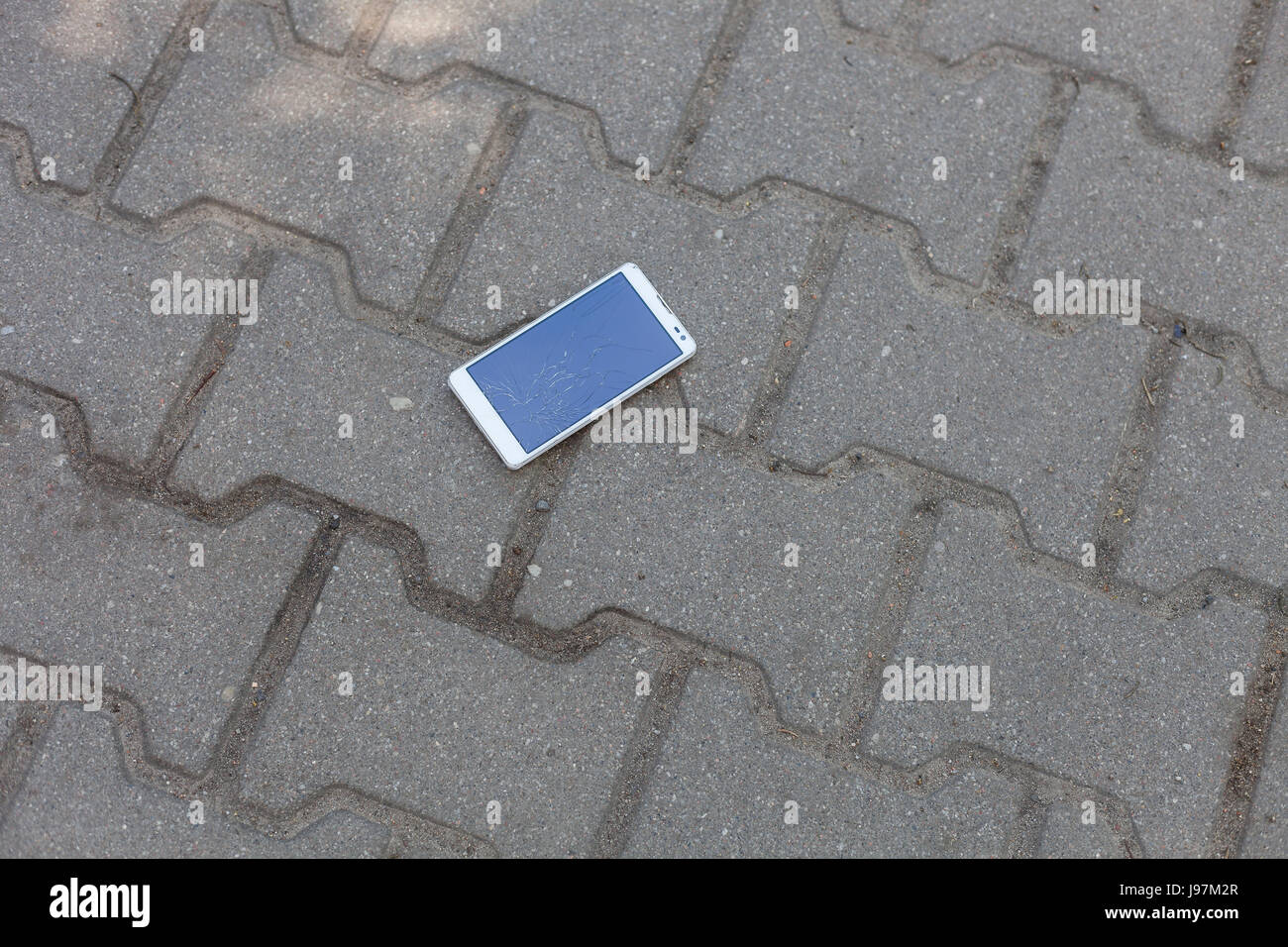 Phone with broken screen lying on the pavement Stock Photo