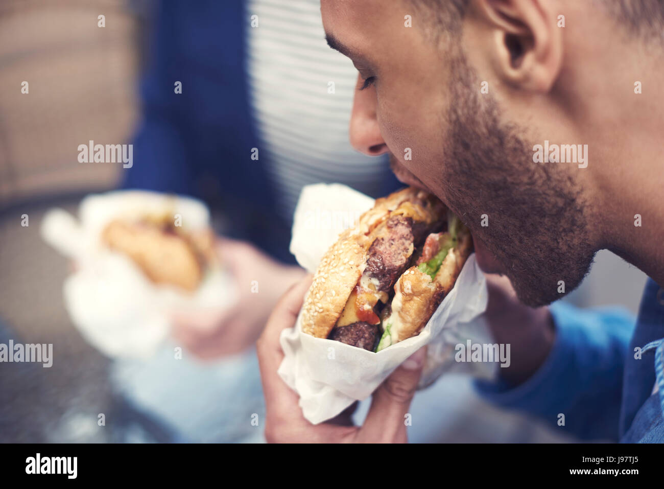 Close up of man eating cheeseburger Stock Photo