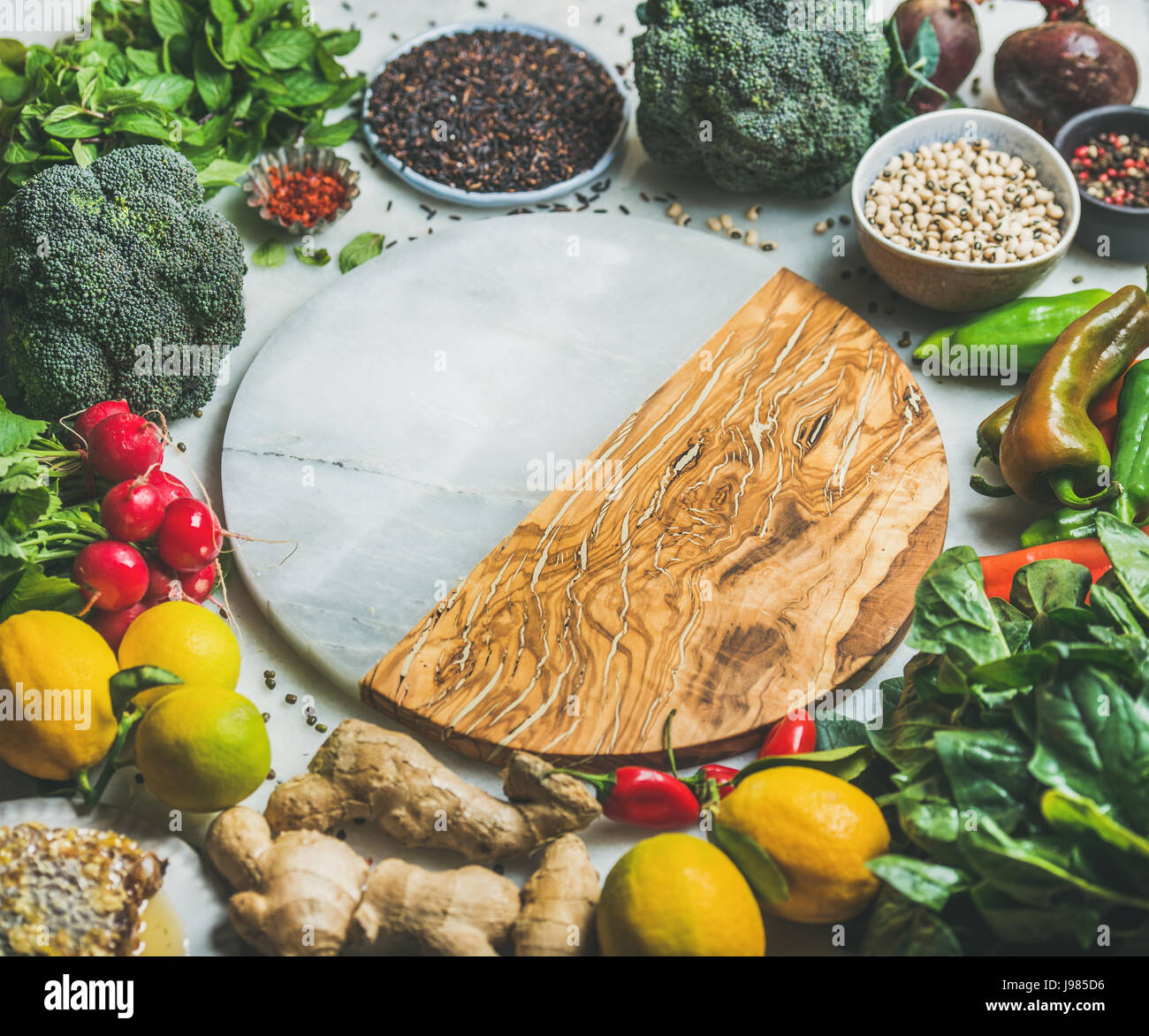 Vegetables, beans, grains, greens, fruit, spices over grey background