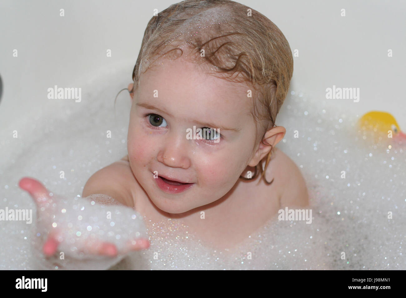 Child, little girl playing in the bath holding her hand up with bubbles