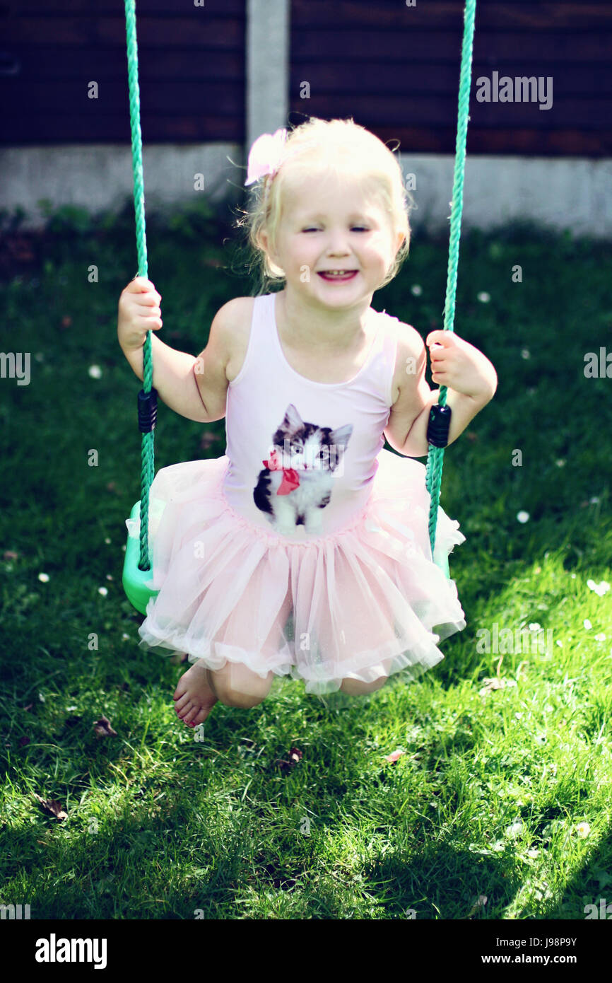 Little girl, child wearing a tutu swinging on a swing in the garden on a  sunny summers day, Dublin Ireland Stock Photo - Alamy