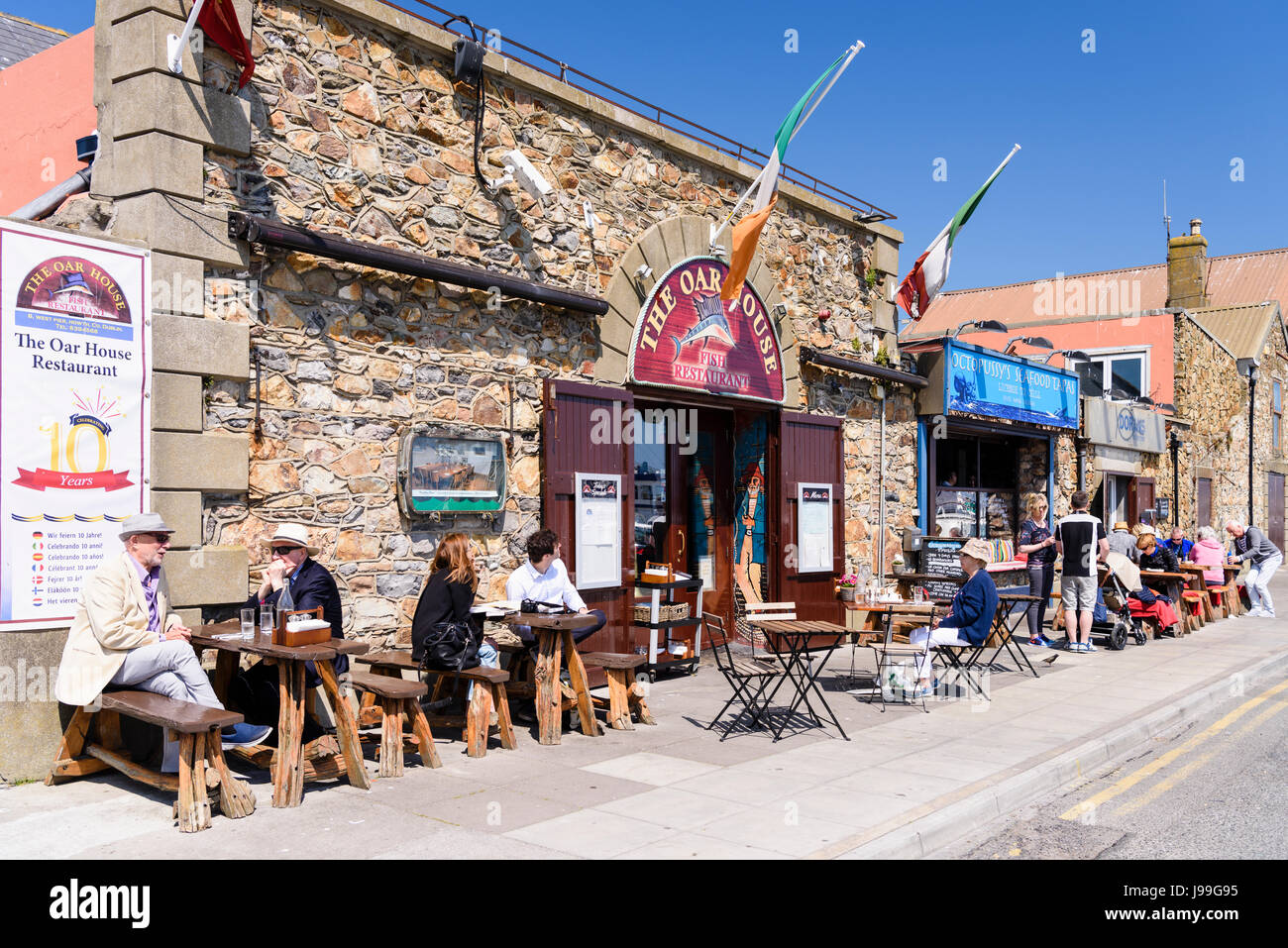 People eating and enjoying a drink in the sun outside a fish restaurant in Howth, Dublin, Ireland. Stock Photo