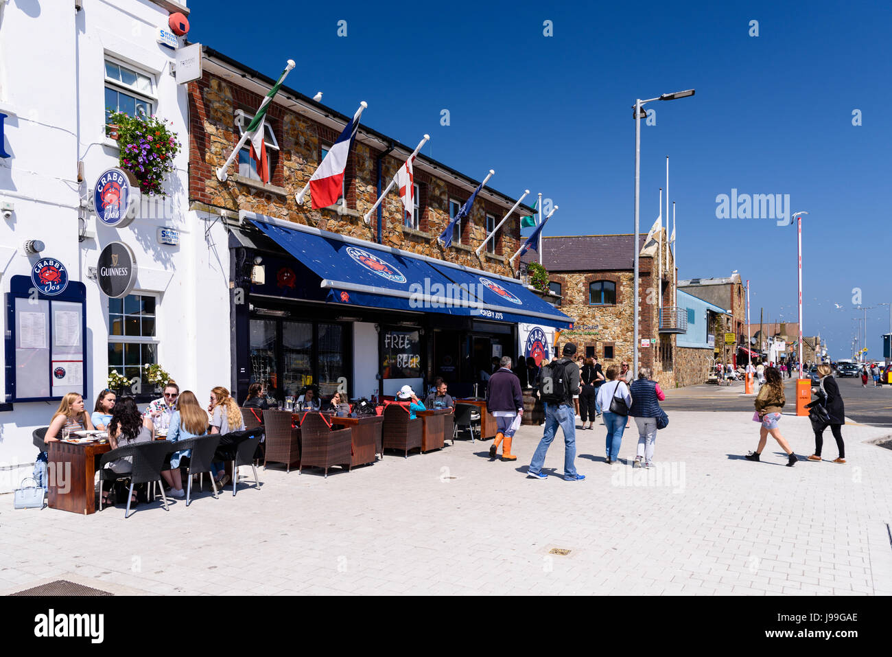 People eating and enjoying a drink in the sun outside a fish restaurant in Howth, Dublin, Ireland. Stock Photo