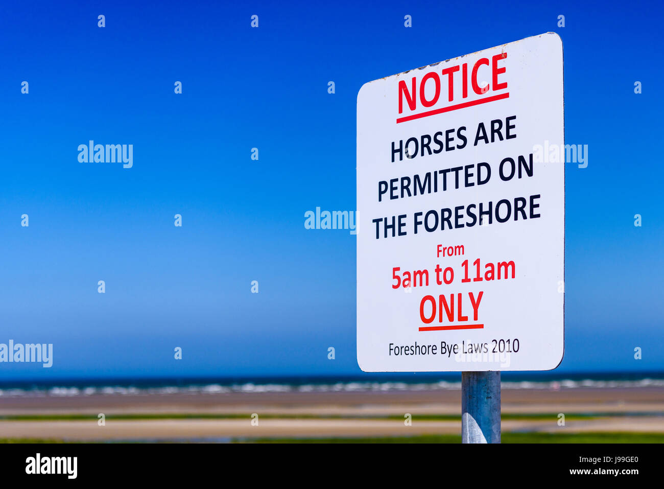 Sign at a beach, advising the public that horses are only permitted on the foreshore between 5am and 11am. Stock Photo