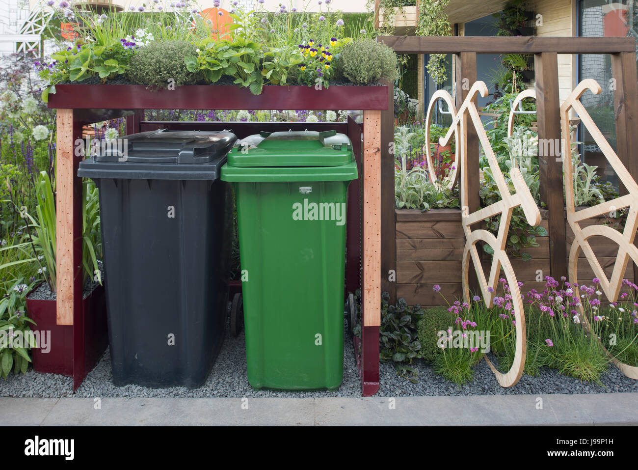 A container for wheelie bins topped with plants in the RHS Greening of Grey Britain Garden at the RHS Chelsea Flower Show 2017, London, UK Stock Photo
