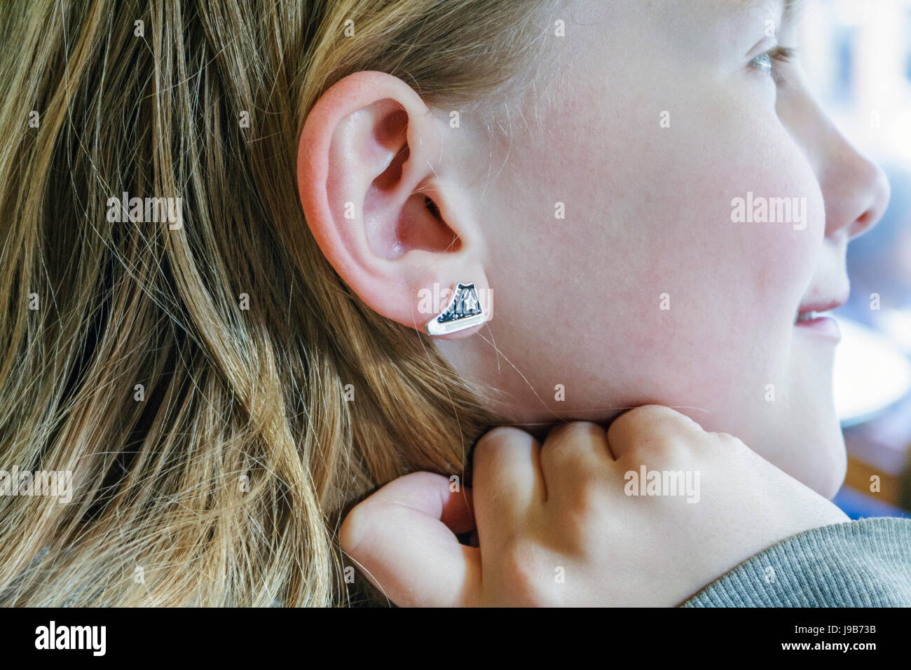Close-up side view of an eleven year old girl showing off her enamel earring  or stud in the form of a Converse-style trainer shoe Stock Photo - Alamy
