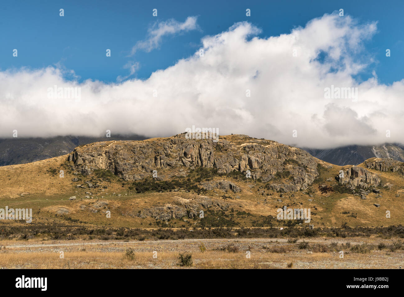 Middle Earth, New Zealand - March 14, 2017: Focus on the Rock of Middle Earth set in a high desert mountainous scenery under blue cloudy sky. Stock Photo