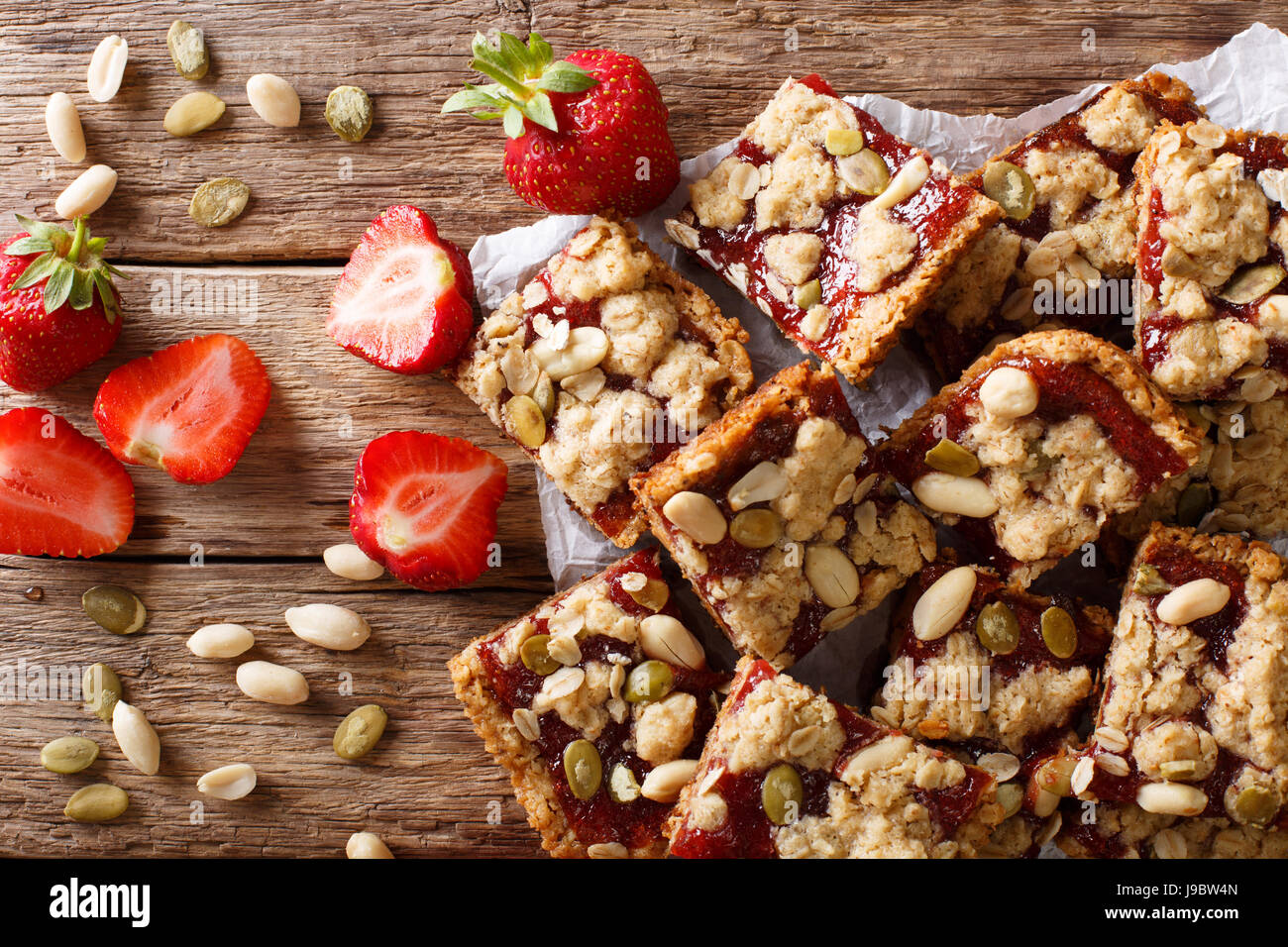Oat bars with strawberries, seeds and nuts close-up on the table. horizontal view from above Stock Photo