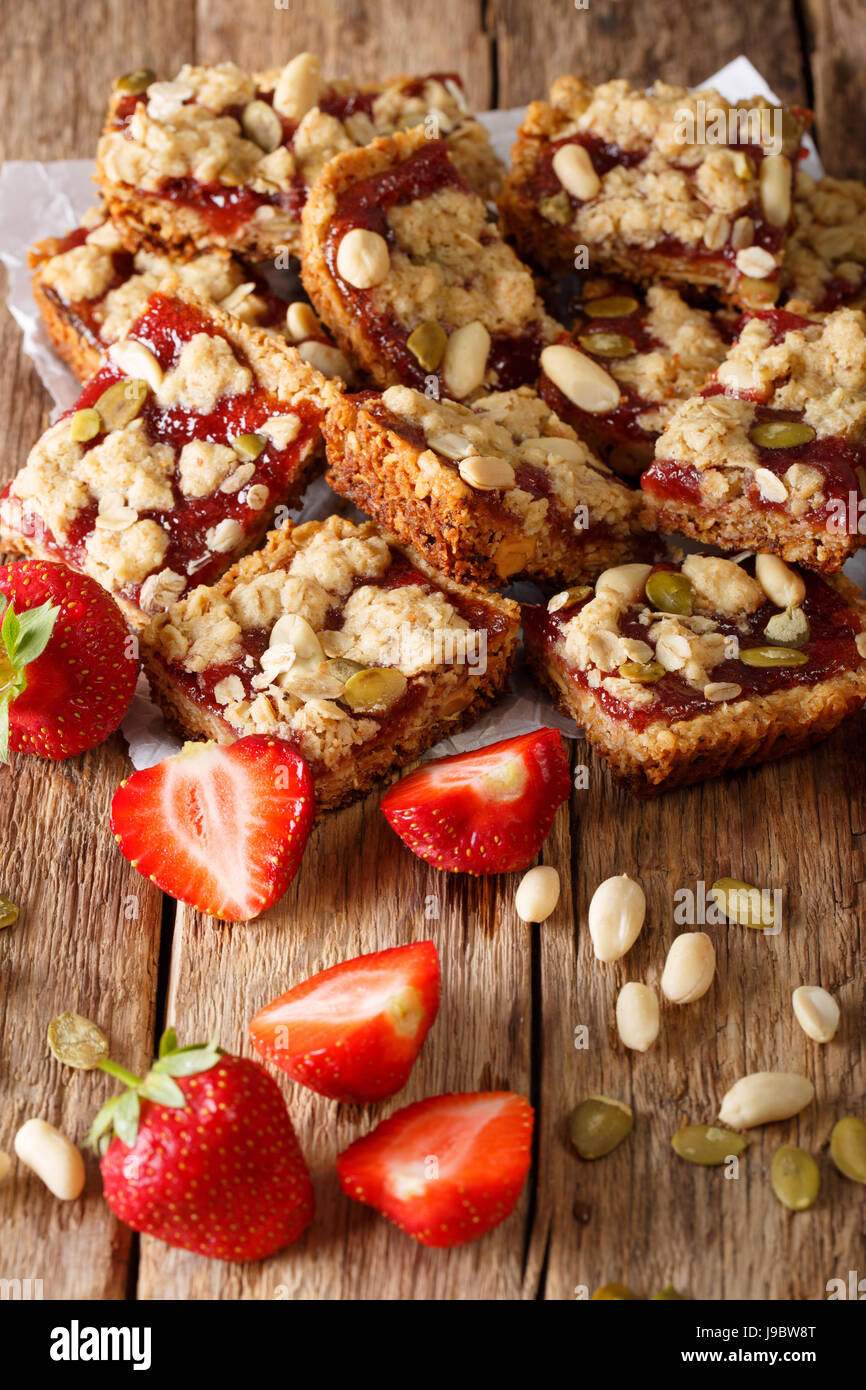 Granola bars with strawberry jam, seeds and nuts close-up on the table. vertical Stock Photo