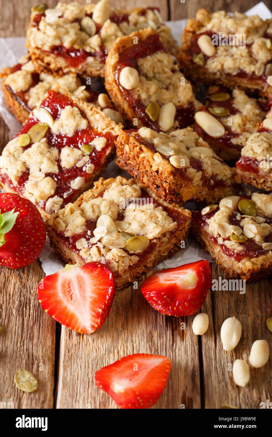 Granola bars with strawberry, sunflower seeds and peanuts close-up on the table. vertical Stock Photo