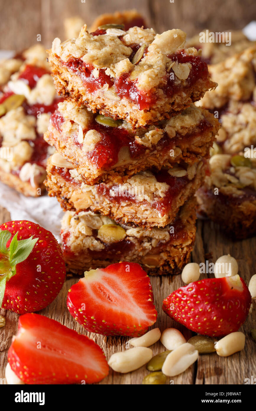 Energy muesli bars with strawberry, pumpkin seeds and peanuts close-up on the table. vertical Stock Photo