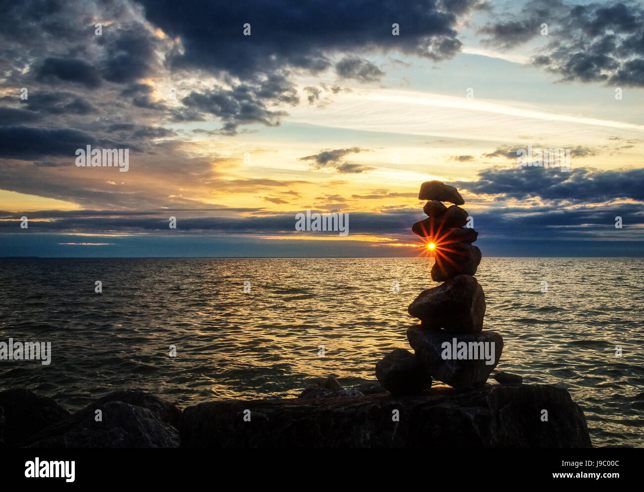 sunrise behind stacked rocks on the beach of Lake Huron Michigan USA Stock Photo