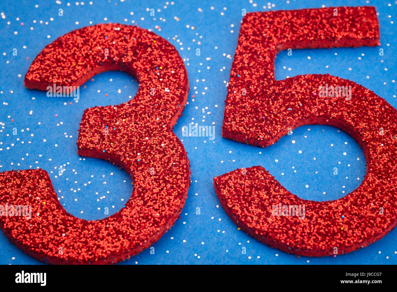 Number thirtyfive red color over a blue background. Anniversary. Horizontal Stock Photo