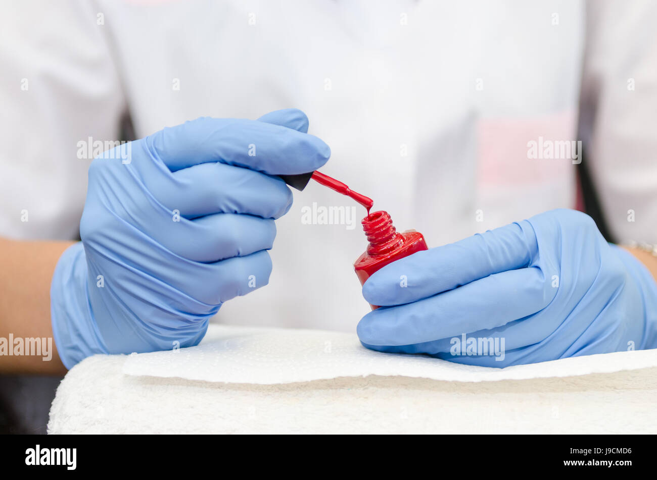 Female hand with gloves opens a bottle of red lacquer Stock Photo