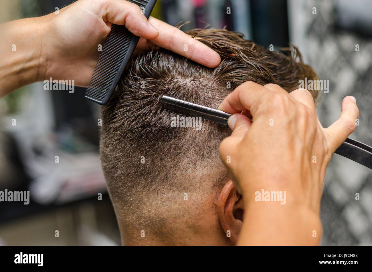 Hairdresser cutting man's hair with toothed razor Stock Photo