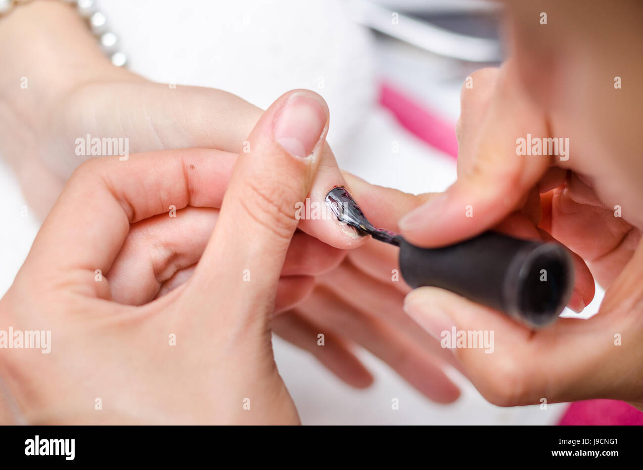 Woman applying black nail polish Stock Photo