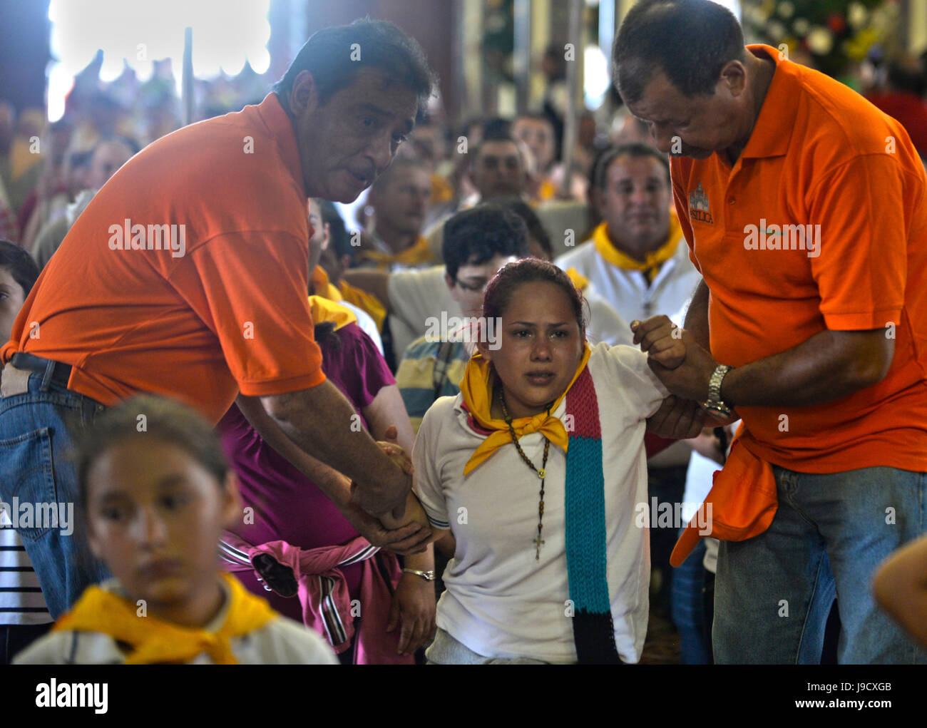 Church aids help a pilgrim crawl to the alter of the Basillica de Nuestra Señora Los Angeles during the annual catholic pilgrimage to the in Cartago,  Stock Photo