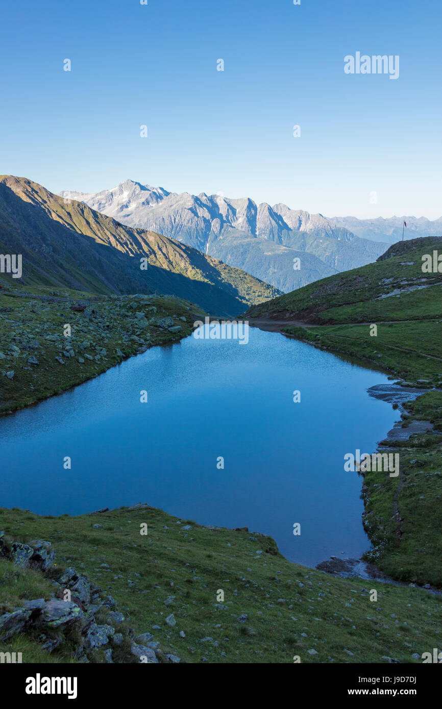 The alpine lake frames the green valley and Rifugio Bozzi, Val Di Viso, Camonica Valley, province of Brescia, Lombardy, Italy Stock Photo