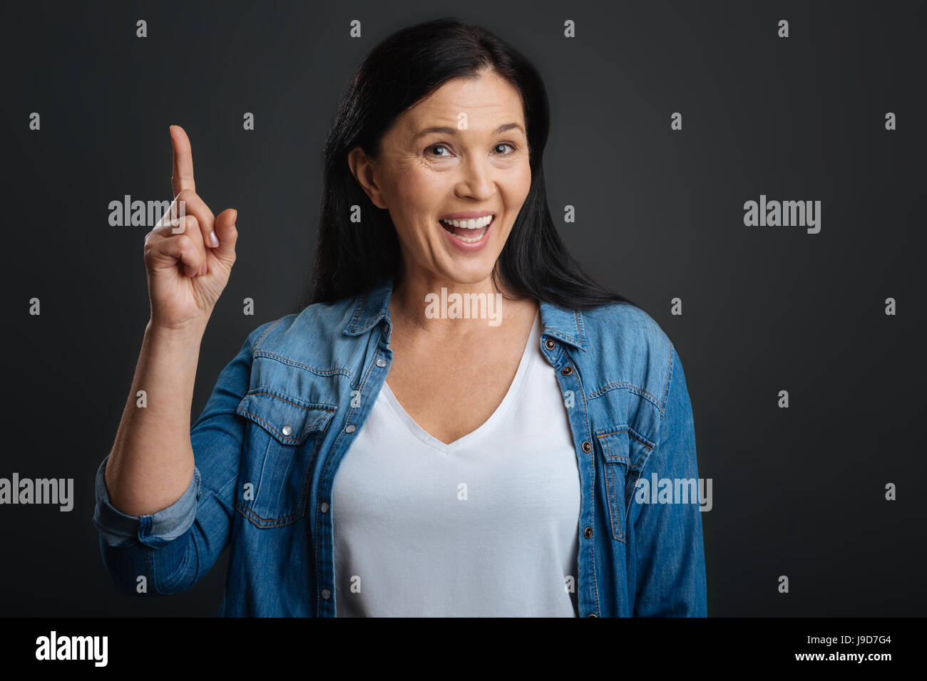 I can prove that. Intelligent polite expressive lady holding her finger up while having a debate with someone and proving her point Stock Photo