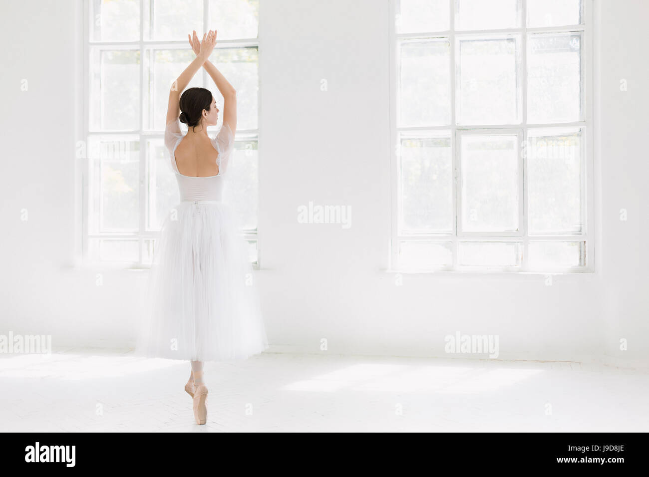 Young and incredibly beautiful ballerina is posing and dancing in a white studio Stock Photo