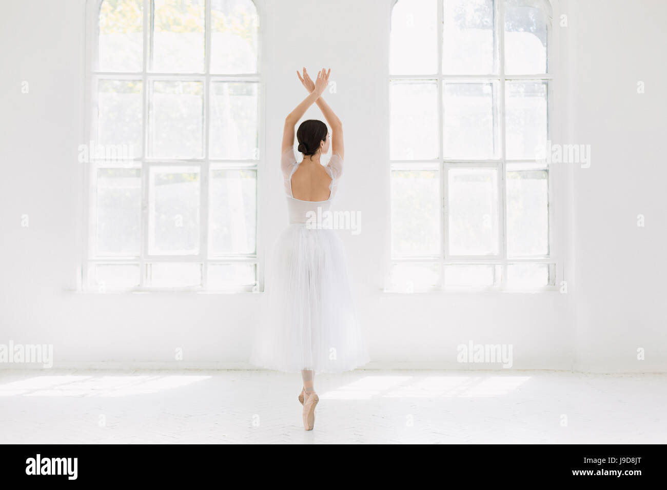 Young and incredibly beautiful ballerina is posing and dancing in a white studio Stock Photo