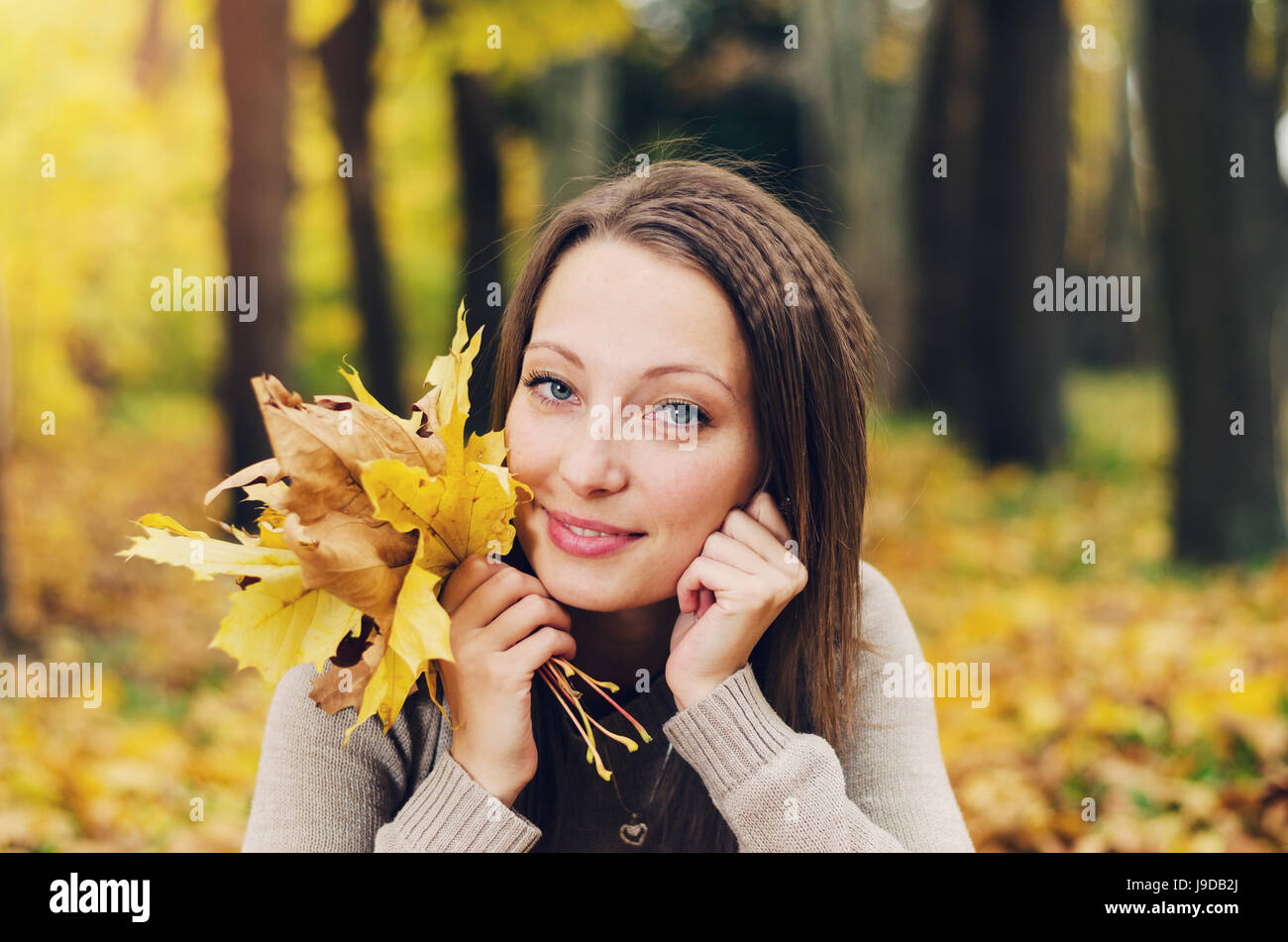 Autumn girl playing in city park. Fall woman portrait of happy lovely and beautiful young woman in forest in fall colors. Stock Photo
