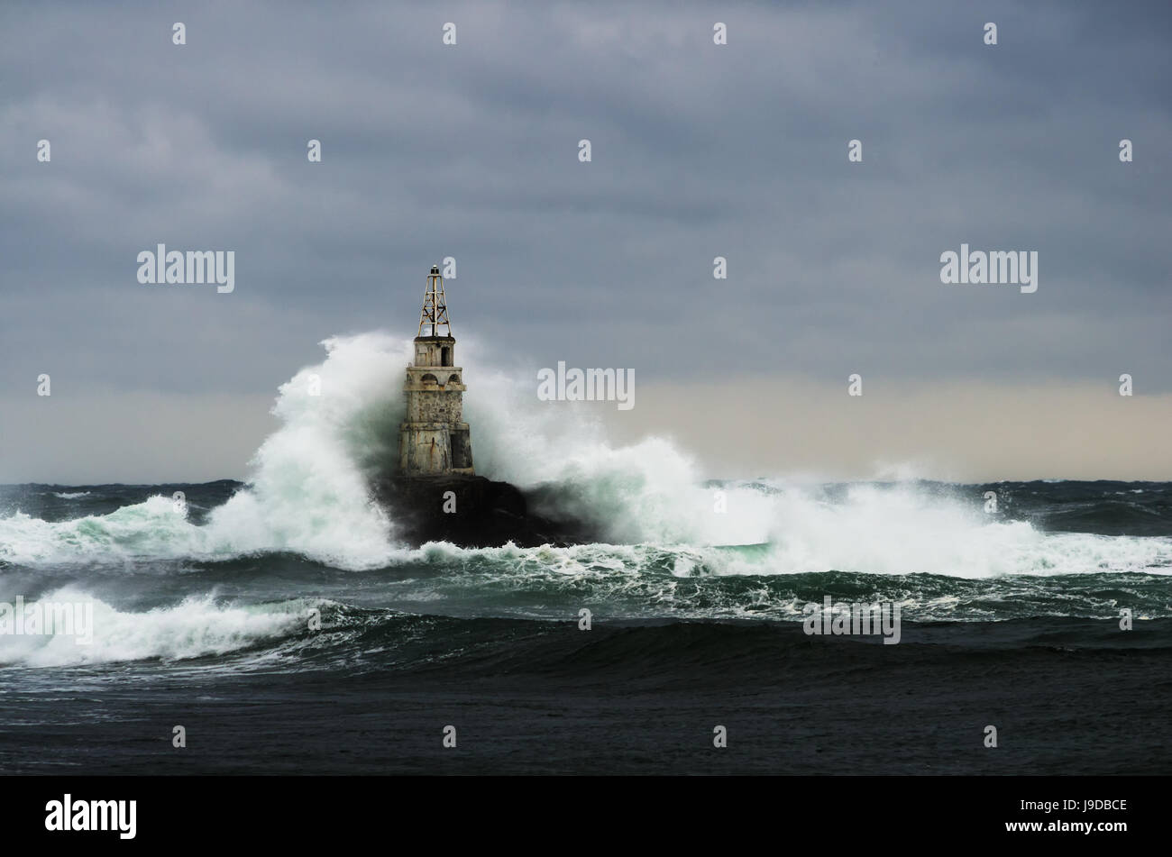 Old lighthouse in the sea in stormy day Stock Photo