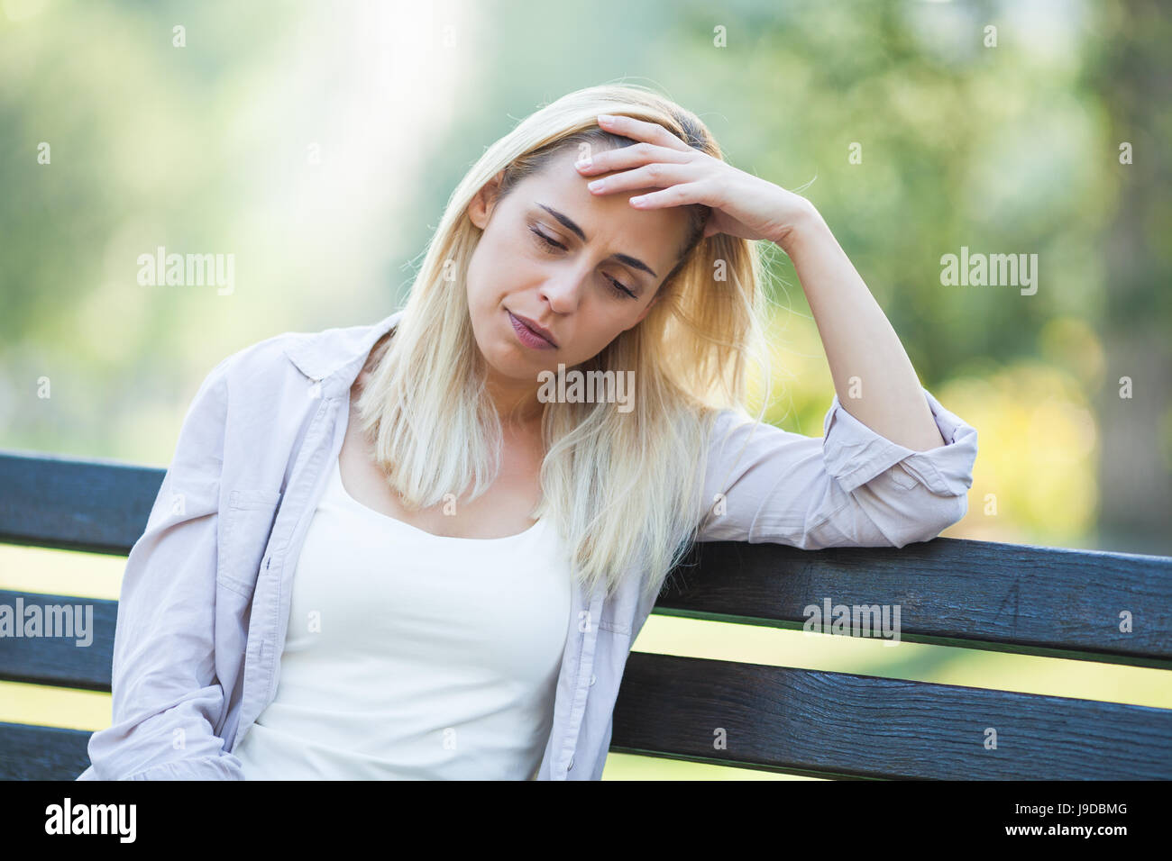 Lonely woman sitting in park in despair. Stock Photo