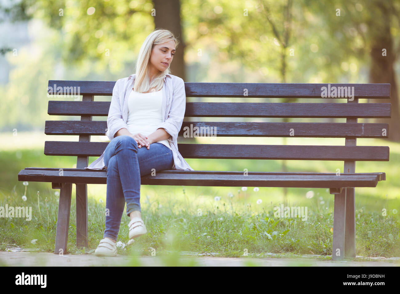Lonely woman sitting in park in despair. Stock Photo