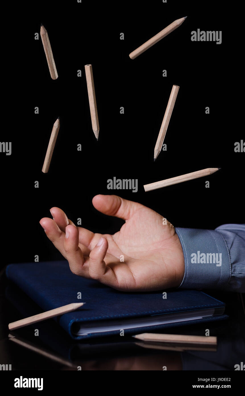 hand with levitating pencils in the office on black background Stock Photo
