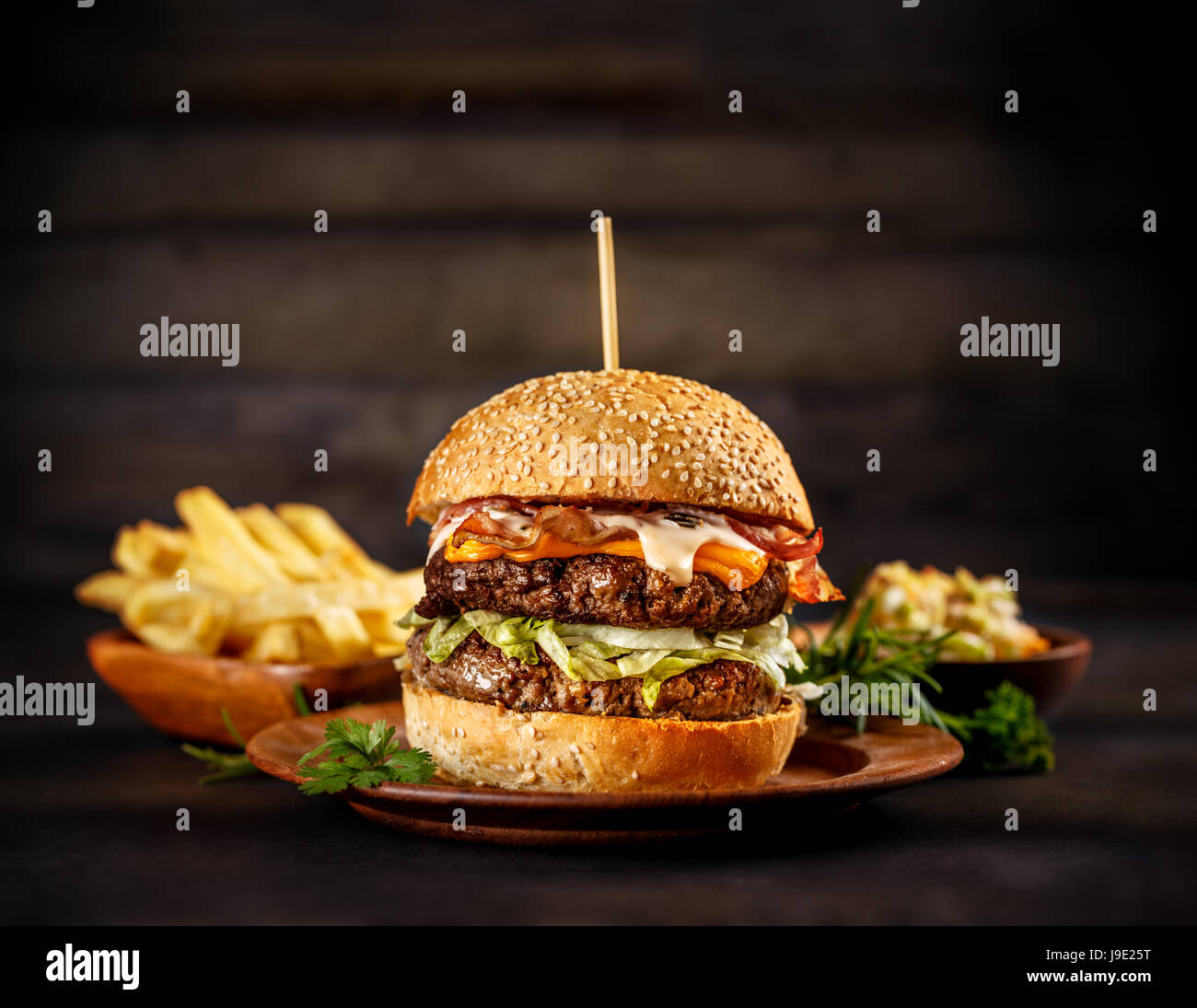 Big beef burger with melted cheese and bacon on wooden plate Stock Photo