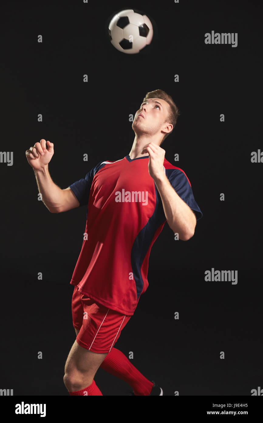 Professional Soccer Player Heading Ball In Studio Stock Photo