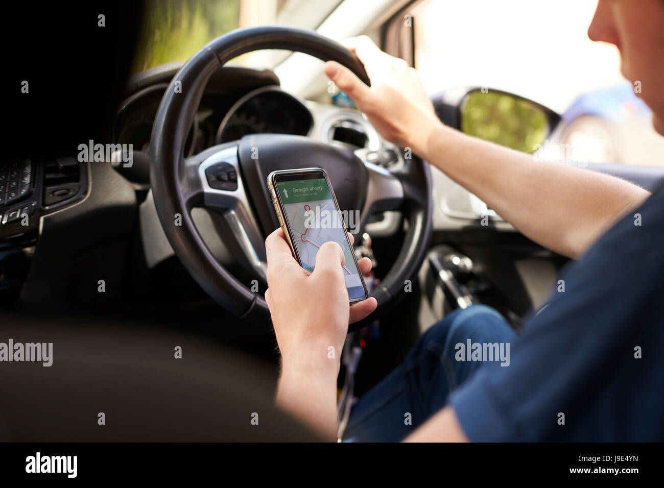 Young Man Using Satellite Navigation on Phone Whilst Driving Stock Photo
