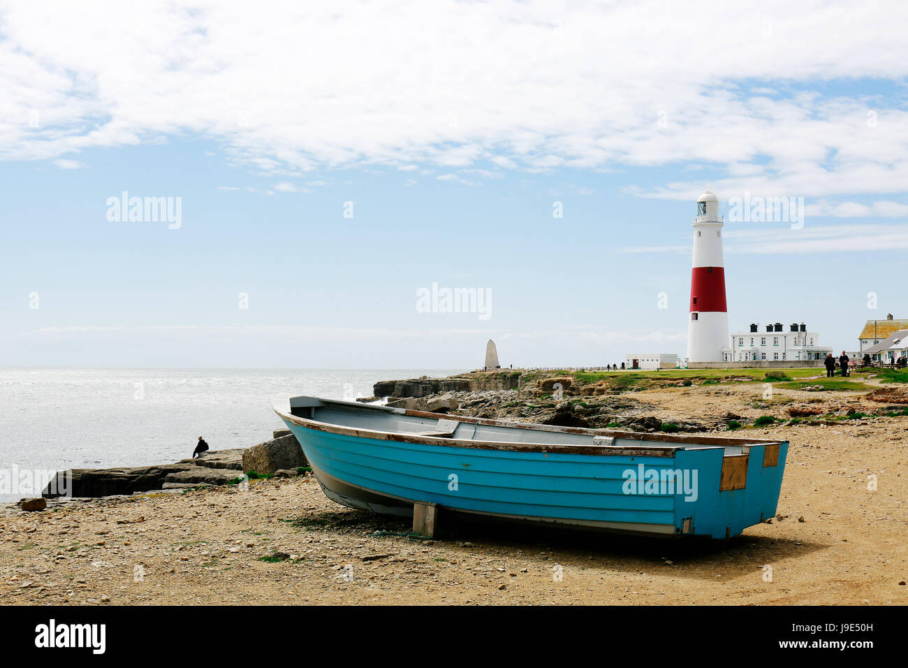 Wooden boat by the seaside and Portland Bill Lighthouse on the Isle of Portland in Dorset, UK on the background Stock Photo