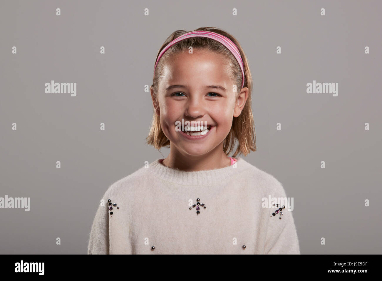 Nine year old girl smiling to camera, head and shoulders Stock Photo