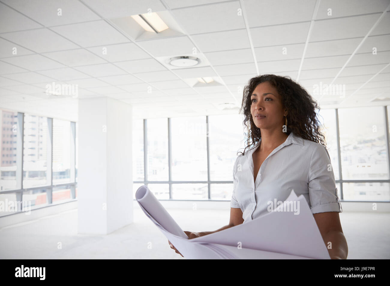 Female Architect In Modern Empty Office Looking At Plans Stock Photo ...