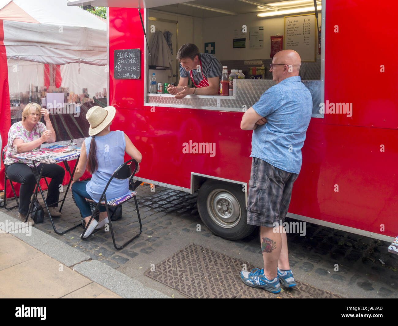 Three customers chatting to the owner of a portable burger bar in a North Yorkshire weekly market Stock Photo