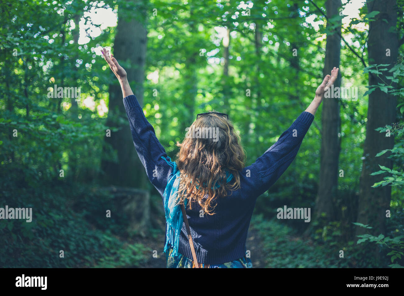 A young woman is raising her arms in the forest Stock Photo - Alamy