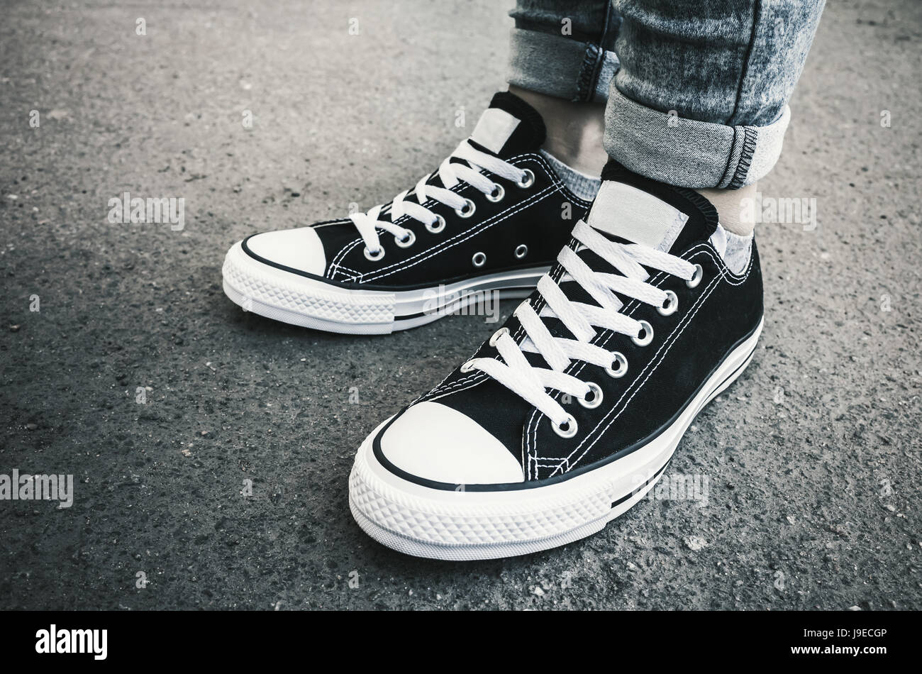 Black and white new sneakers, teenager feet stand on dirty urban pavement.  Closeup photo with selective focus and vintage tonal correction filter  Stock Photo - Alamy