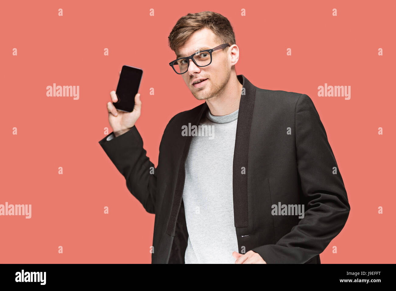 The young caucasian businessman on red background talking on cell phone Stock Photo
