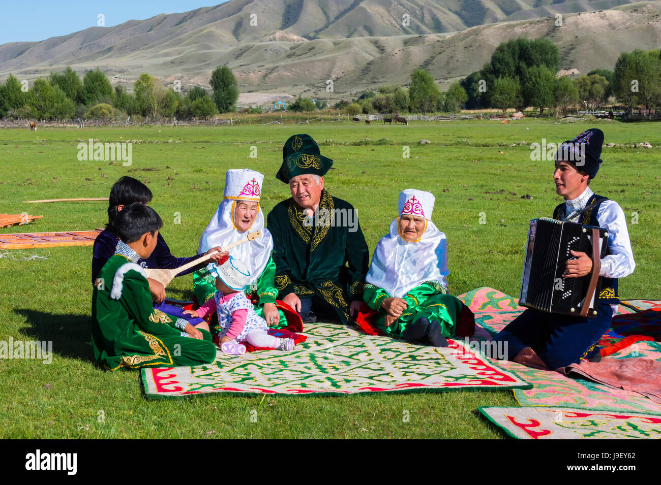 Kazakh family in traditional clothes listening to the music of an accordion player, For editorial Use only, Sati village, Tien Shan Mountains, Kazakhs Stock Photo