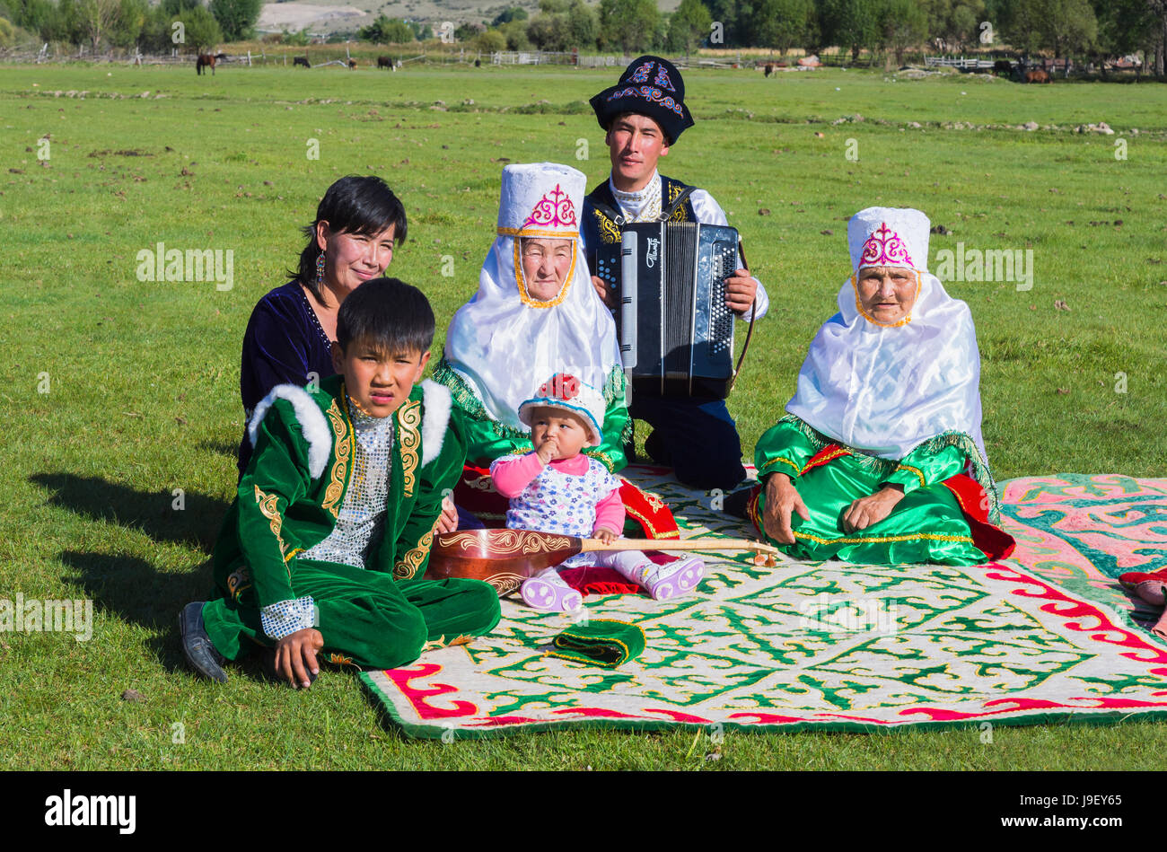 Kazakh family in traditional clothes listening to the music of an accordion player, For editorial Use only, Sati village, Tien Shan Mountains, Kazakhs Stock Photo