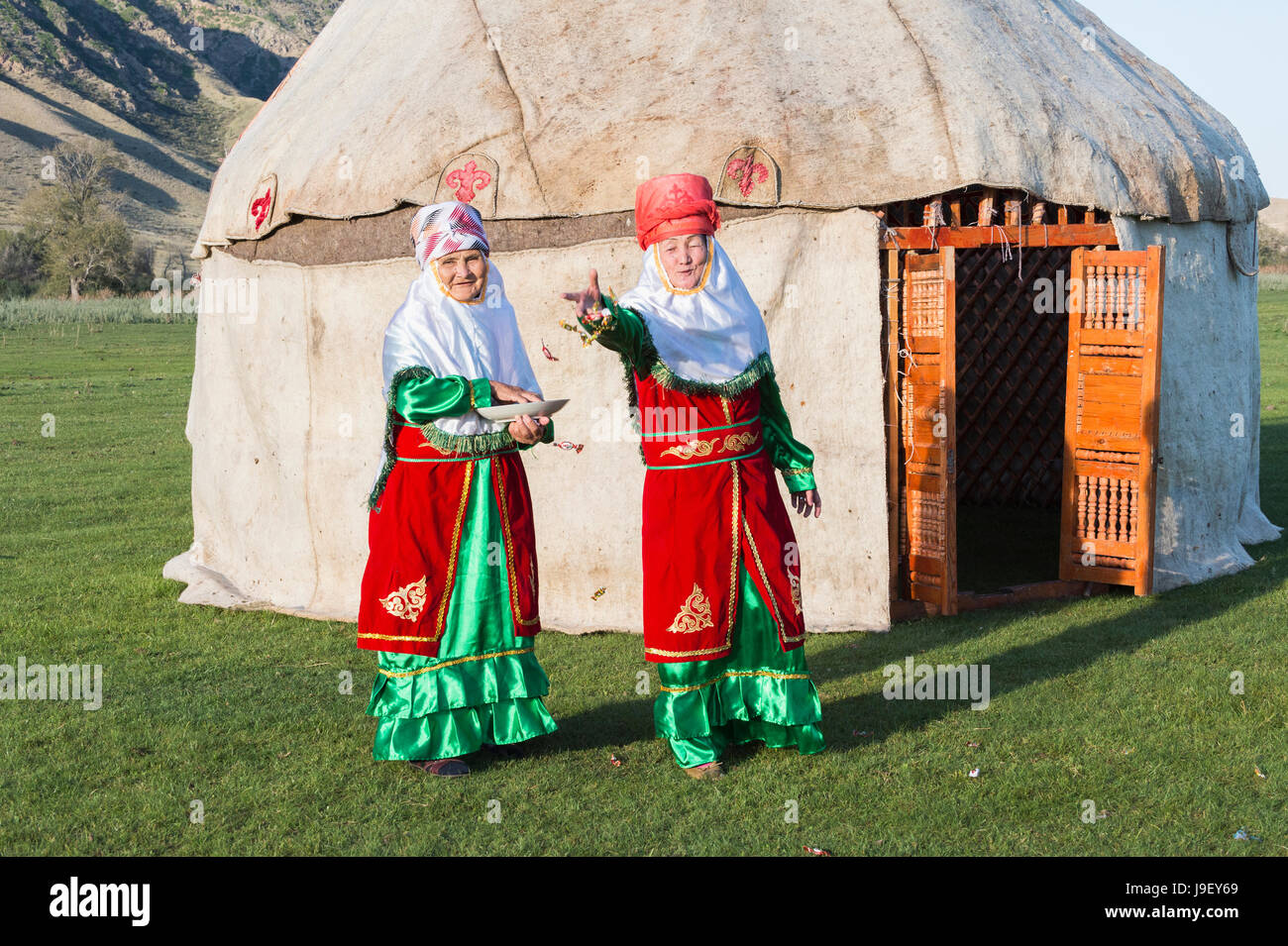Two Kazakh women in traditional clothes in front of a yurt welcoming guests with candies, For editorial Use only, Sati village, Tien Shan Mountains, K Stock Photo
